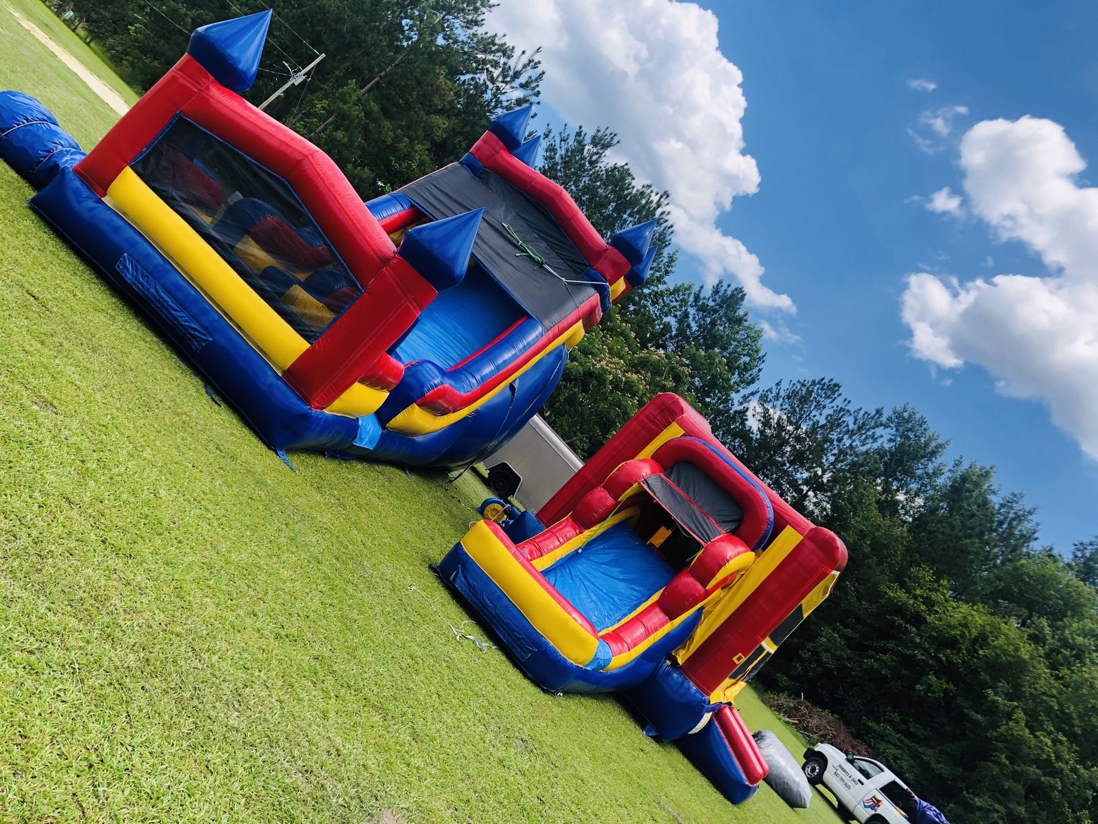 Colorful bounce house combo units with striped towers set up in a field