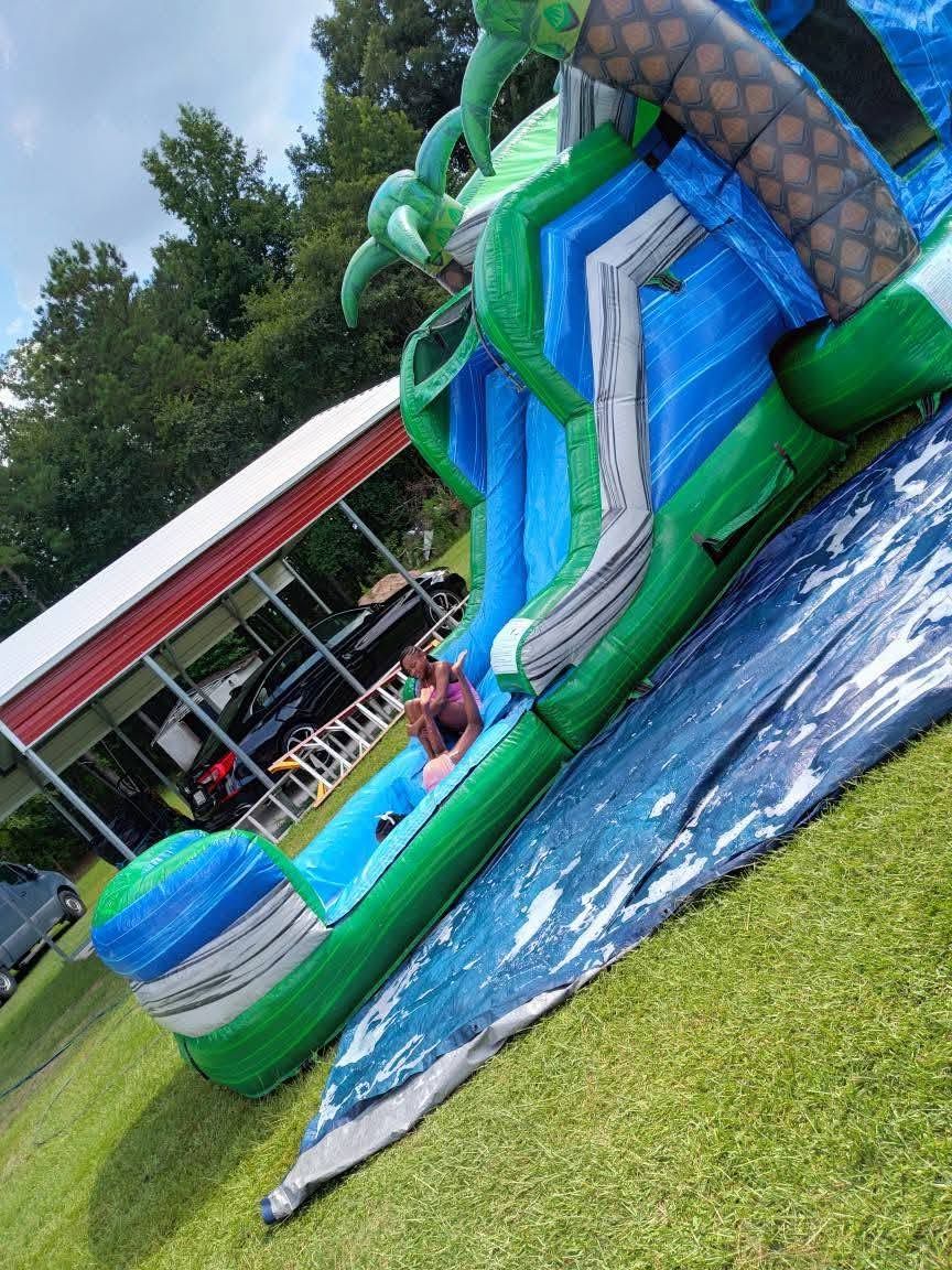 Green and blue tropical water slide combo units on a sunny day